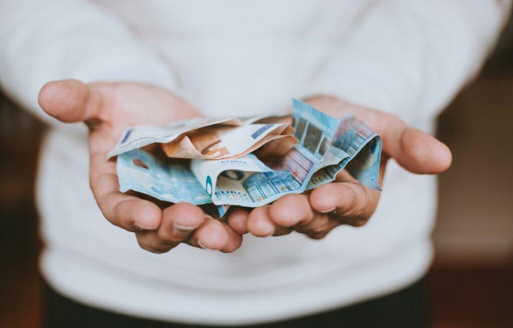 Hands holding euro notes, symbolizing financial independence, semi-retirement, and frugal living for family life.